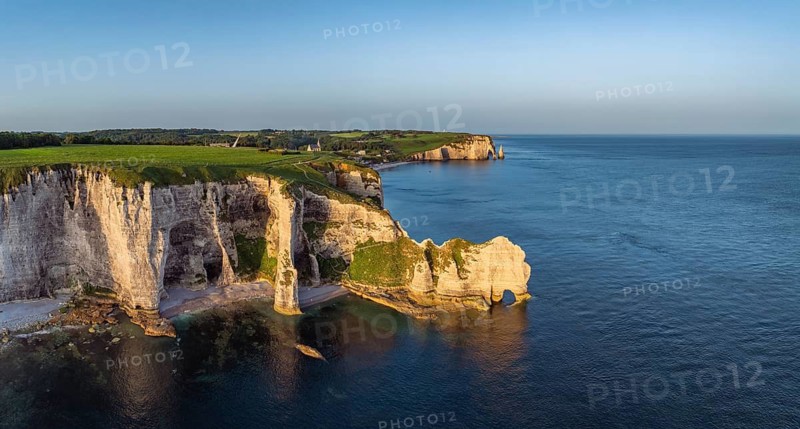 Aerial view, panorama of the Porte d'Amont rock formation, Falaise d'Amont shortly after sunrise, a landmark and natural beauty on the chalk coast with the distinctive rock gate, behind it the holiday resort of Étretat with the swimming beach, on the right the Porte d'Aval rock formations, Alabaster Coast, La Côte d'Albâtre, chalk cliffs, English Channel, Seine-Maritime, Normandy, France