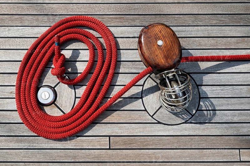 Red rope or line and pulley or block, neatly arranged on the wooden deck of a sailing ship, Aeolian or Aeolian Islands, Sicily, Southern Italy, Italy