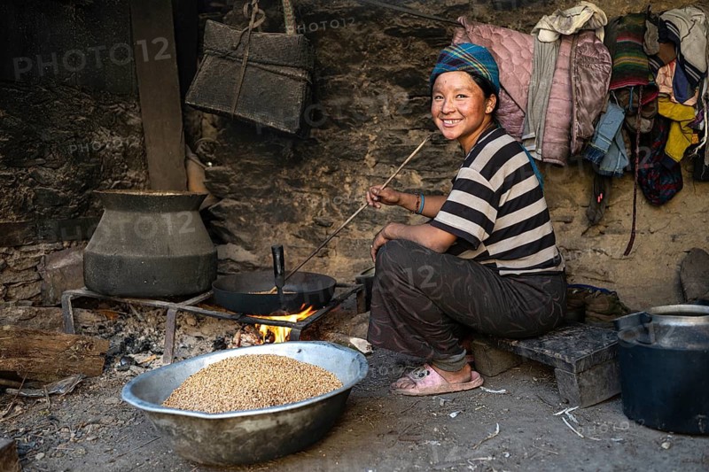 Young woman, Nepalese woman, local of the Tsumba Tibetan ethnic group roasting barley over a fire, Ripchet, Tsum Valley, Himalayas, Nepal