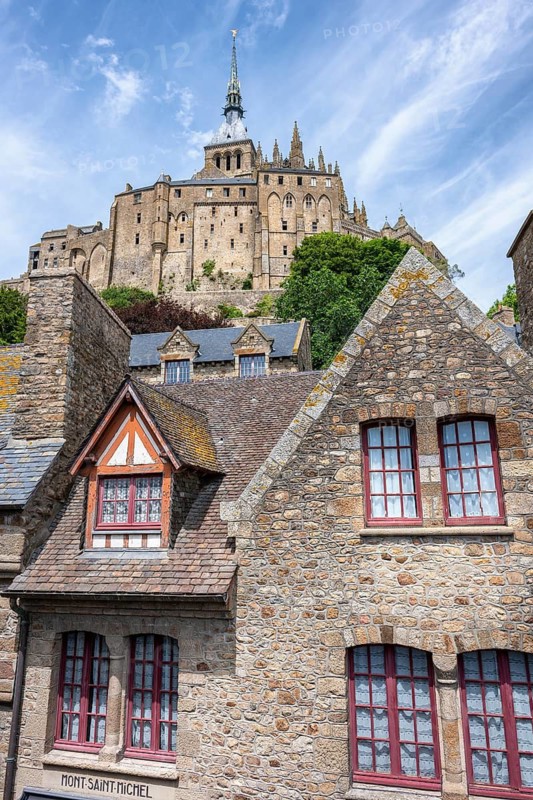 Medieval alley and traditional stone houses within the fortress walls of Mont-Saint-Michel. In the background rises the famous Benedictine monastery, tourist attraction, UNESCO World Heritage Site, Pontorson, Manche department, Normandy, France