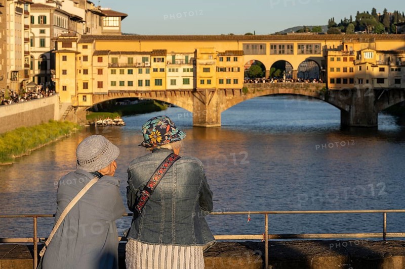 Tourists stand on Ponte Santa Trinita and look towards Ponte Vecchio, Florence, Italy