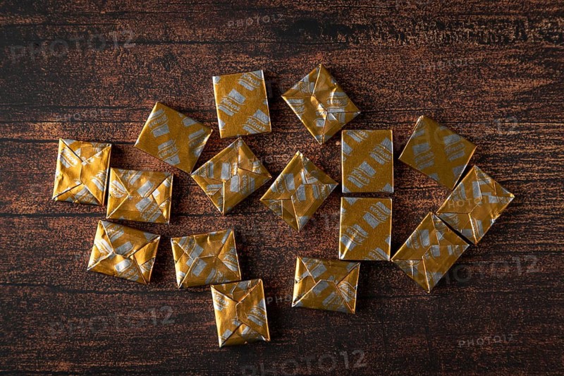 Several soup cubes in golden packaging on a wooden table