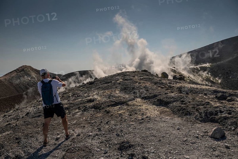 Tourist stands at the crater rim and photographs rising sulfur clouds, Vulcano, Aeolian or Lipari islands, Sicily, southern Italy, Italy