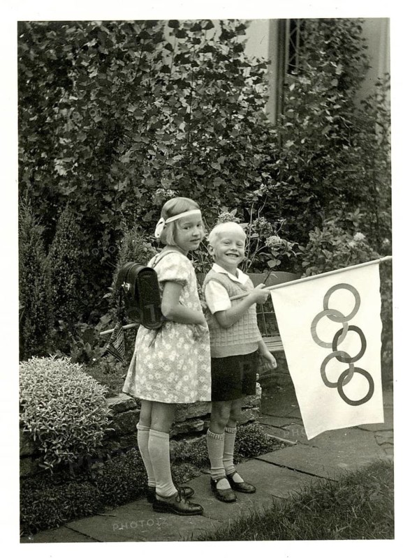 Berlin, Olympics 1936, Olympic flag, two children posing in a garden with a flag showing Olympic rings, schoolchildren, satchel, Solz, way to school, siblings