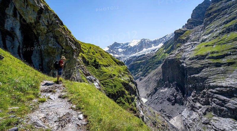 Mountaineers on a narrow hiking trail in a rocky gorge with waterfall, mountain landscape with Grindelwald-Fiescherfirn glacier, Bernese Alps, Bernese Oberland, Switzerland