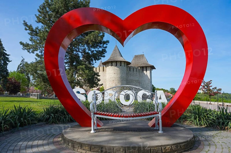 Large red heart sculpture with SOROCA lettering and castle in the background in a park, Soroca Fortress, Soroca, Republic of Moldova, Moldova
