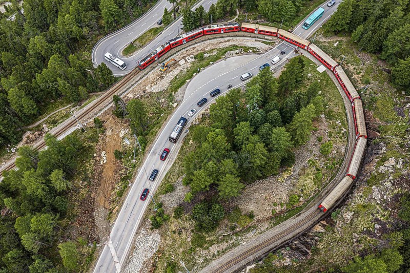 Red train of the Rhaetian railroad line, Bernina Express, 180 degree turn at the Montebello curve, aerial view, Morteratsch, Switzerland
