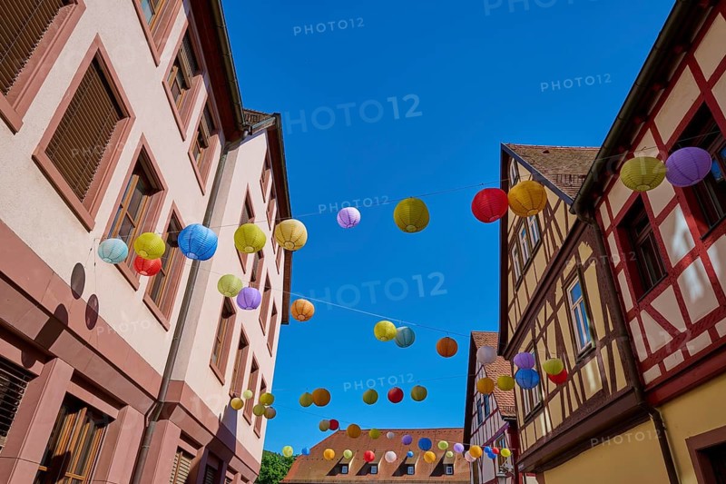 Colourful lanterns hang over a street with half-timbered houses on a sunny day, Lohr am Main, Schneewittchenstadt, Main-Spessart district, Mainfranken, Lower Franconia, Bavaria, Germany