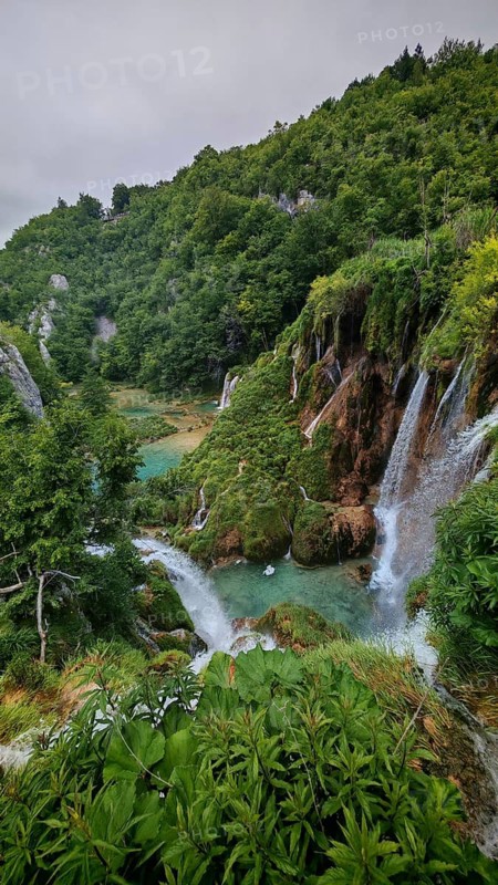 Cascading waterfalls in a green setting full of lush plants and rocky elevations, Plitvice Lakes National Park, Croatia