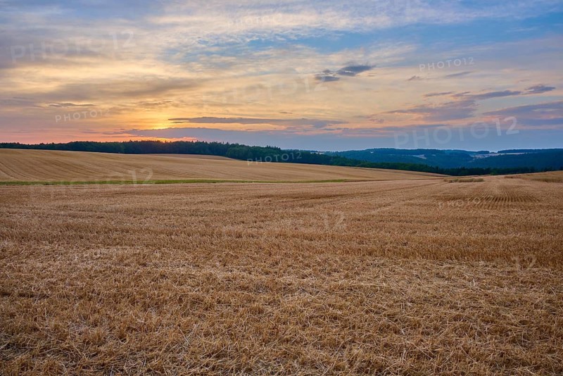 Wide stubble field under a colorful sunset sky with clouds, summer, Neudorf, Amorbach, Odenwald, Bavaria, Germany
