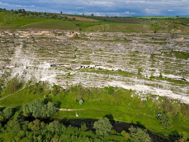 Steep cliffs with lush vegetation and a river course at the base in a green setting, aerial view, cave dwellings, Raut River, Raut, Old Orhei, Orheiul Vechi, archaeological site, protected landscape area, Orhei district, Republic of Moldova, Moldova