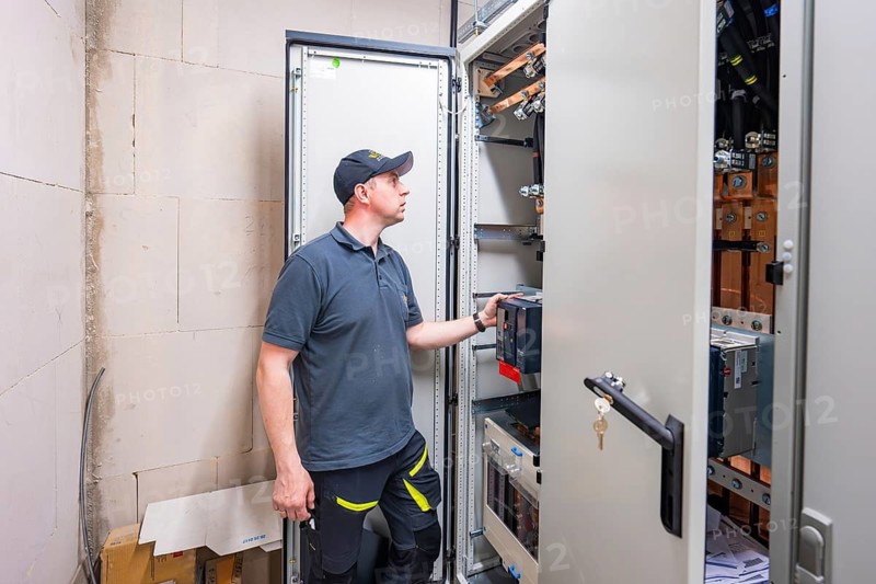 Technician checks the electronics in the control cabinet in an industrial environment, electrical system for PV system, industrial customer, Mühlacker, Germany