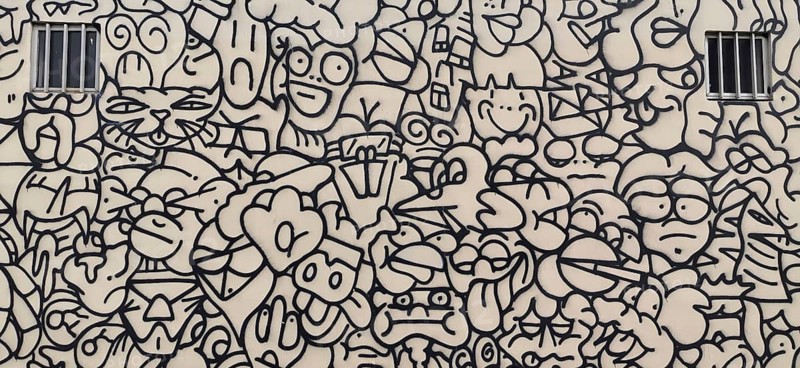 Wall painting of a house façade in black and white with abstract comic faces and shapes, Lisbon, Portugal