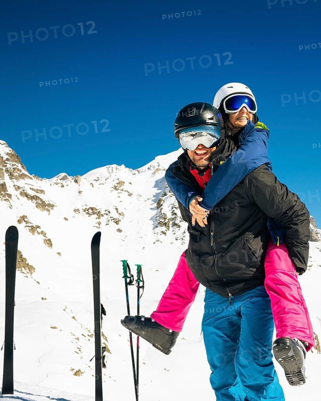 Young caucasian couple pose hug enjoying looking at snowy mountains range in winter. Get away skiing holidays lifestyle. Tetnuldi ski resort viewpoint. Caucasus mountains high altitude freeriding