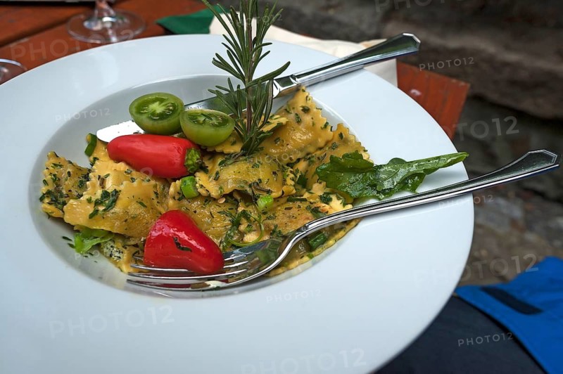 Ravioli with fresh vegetables topped with a sprig of rosemary