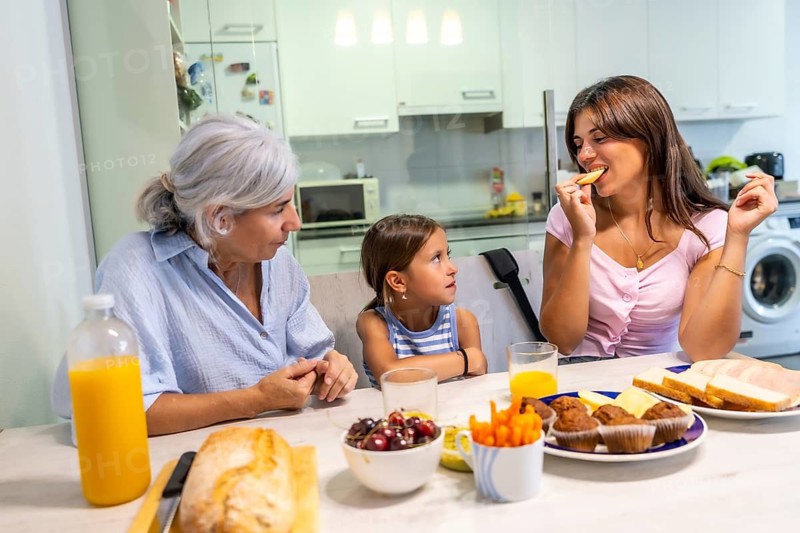 Multi generational female family members. Grandmother. Mother. And granddaughter. Sitting at the kitchen table