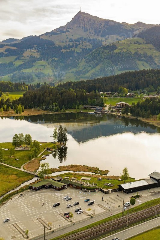 Panoramic view of a lake with mountains in the background and a parking lot in the foreground, Schwarzsee circular trail, Kitzbühel, Austria