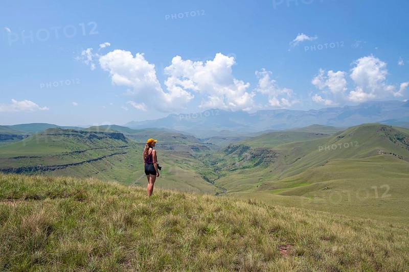 Green hills and valleys, young woman hiking through landscape, Worlds View Hike, Drakensberg, South Africa
