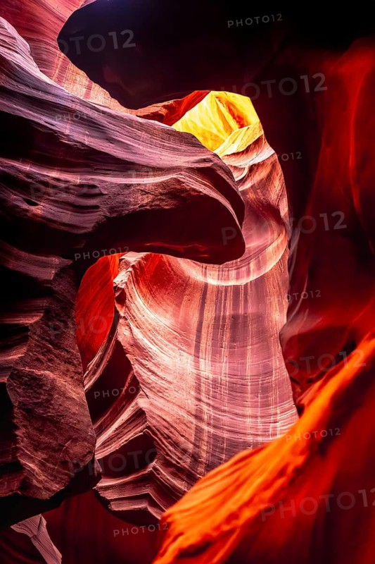 Antelope canyon winding sandstone walls with smooth, wavy erosion patterns, glowing opening above and vibrant red orange and purple light creating an abstract, sculpted landscape
