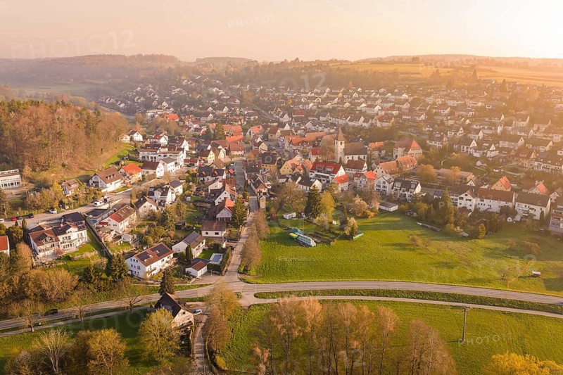 Village with church and green areas in hilly landscape at sunset, Deufringen, Aidlingen, Heckengäu region, Böblingen district, Germany