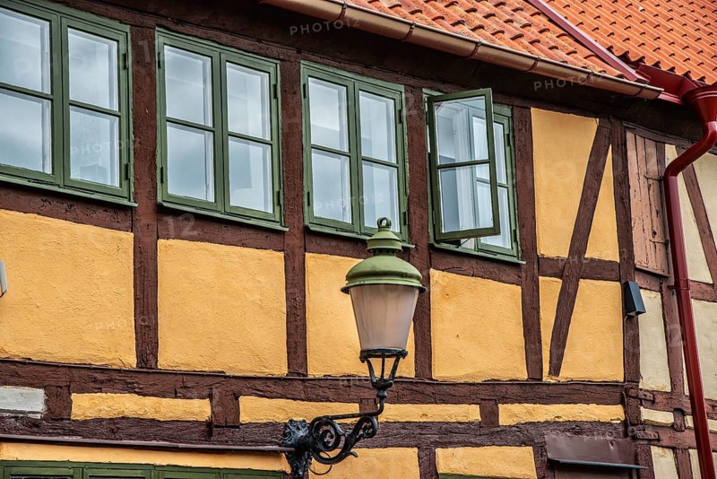 Part of the facade with windows and street lamp of an older half-timbered house in Ystad, Skåne County, Sweden, Scandinavia