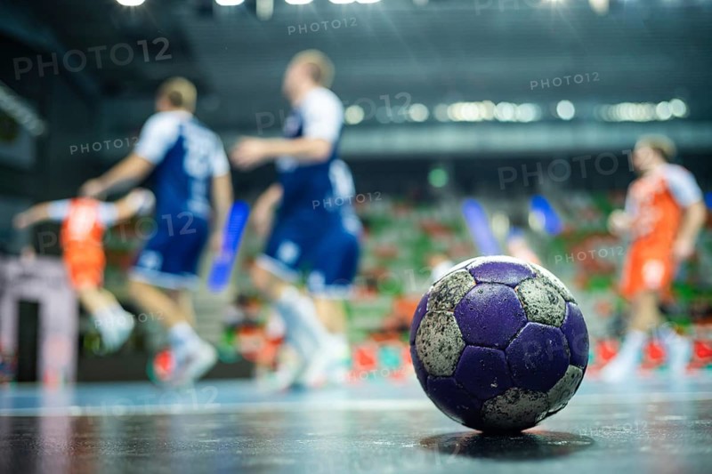 The handball ball laiyng on the parquet and handball match in the background in Lubin, Poland
