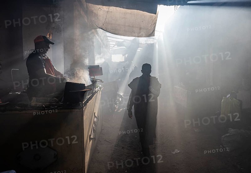 A Moroccan man walks past a food stash, the air is saturated with smoke, smoke from a grill fire, souk bazaar, Marrakech, Maghreb, southern Morocco, Morocco