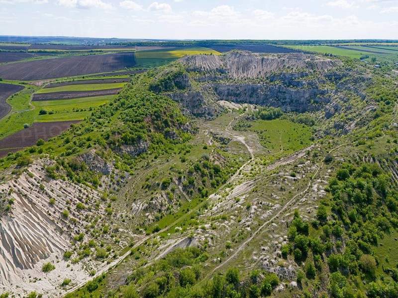 Extensive rocky landscape with green hills and isolated vegetation under blue sky, aerial view, former limestone quarry, Fetesti, Little Switzerland of Moldova, unusual landscape forms, Edinet District, Edine?, Republic of Moldova, Moldova