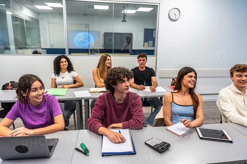 Young students participating and smiling while attending a lecture or class in a university or college setting, actively engaging in higher education and collaborative learning