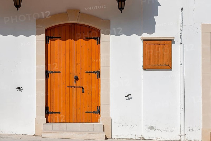 Wooden door and shutters on white building in Mediterranean architecture, sunny with shade, Omodos, Cyprus