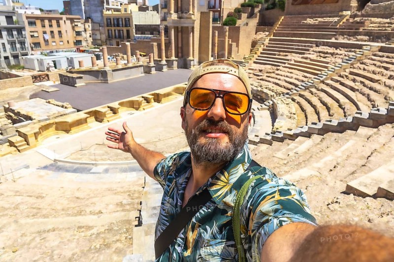 Happy traveler taking a selfie at the ancient roman theatre in cartagena, murcia, spain, exploring historical ruins and experiencing cultural tourism on a sunny day
