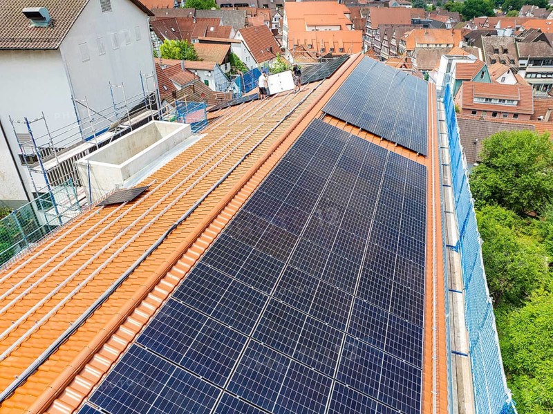 Solar module installation on tiled roof with urban background, new PV system at Heinrich-Immanuel-Perrot secondary school, city of Calw, Germany