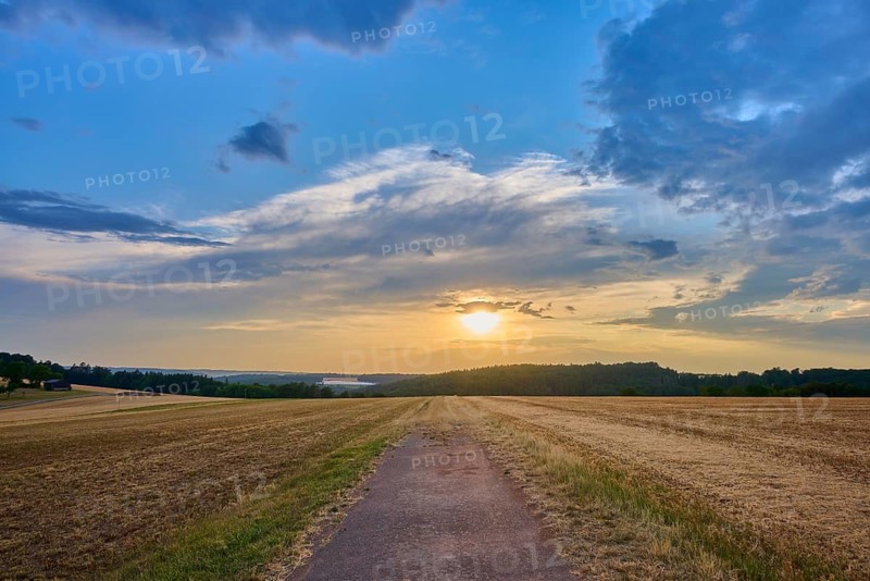 Small path leads through a field at sunset surrounded by a dramatic sky, summer, Reichartshausen, Amorbach, Odenwald, Bavaria, Germany