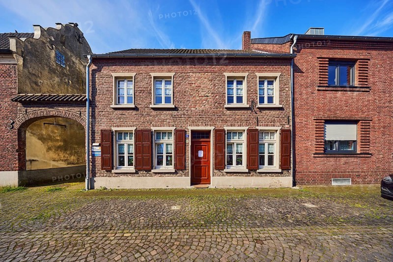 Old town, historic city center, historic brick buildings, façade with windows and shutters, archway, downpipes, roadway, street, paving stones, blue sky, cirrus clouds, Neustraße, Wachtendonk, Kleve district, North Rhine-Westphalia, Germany