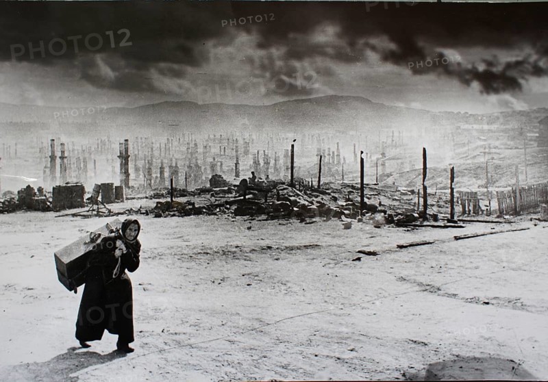 Scorched Earth, Northern Front, Murmansk, Soviet Union 1941 Variant 3 with manipulated skies J. Chaldej about this photo: 'Hitler had said: 'Murmansk must be taken. ' He wanted to prevent the British from supporting the Soviet Union. Murmansk was bombed for a year. On June 22, 1942, Hitler gave the order to burn Murmansk down for good. The city consisted primarily of wooden houses. 350, 000 incendiary bombs were dropped for a day. I discovered the old woman with her suitcase after one of the bombings in 1941. She saw that I had a camera, put down the suitcase and said: 'Aren't you ashamed to record our misfortune? '