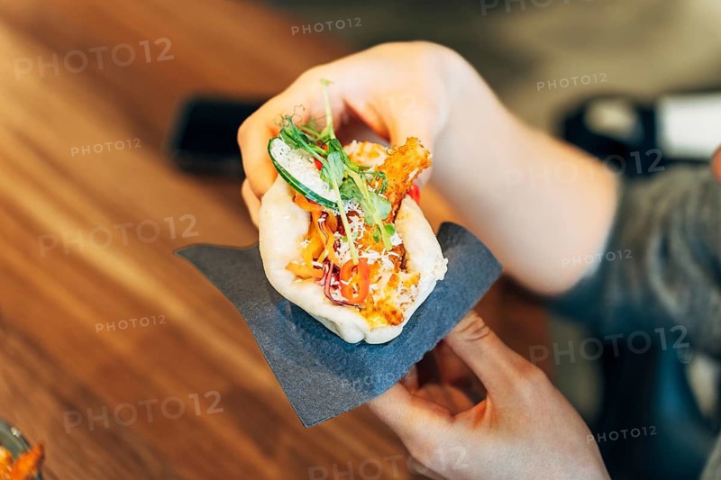 Close-Up of a Womans Hands Holding a Freshly Made Bao Bun with Crispy Filling