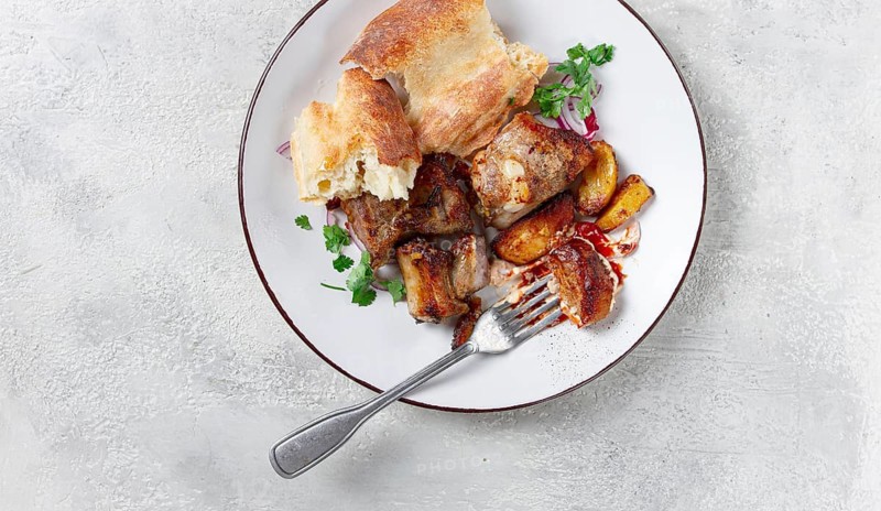 A plate with leftover pork kebab, with bread, on a white plate, close-up, there are no people