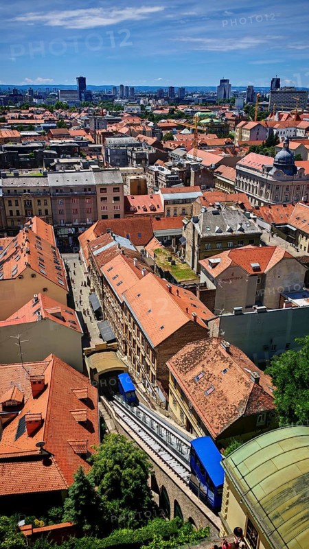Panoramic view from Lotrscak Tower of an urban landscape with red roofs and a cable car going down a gorge-like road, Zagreb, Croatia