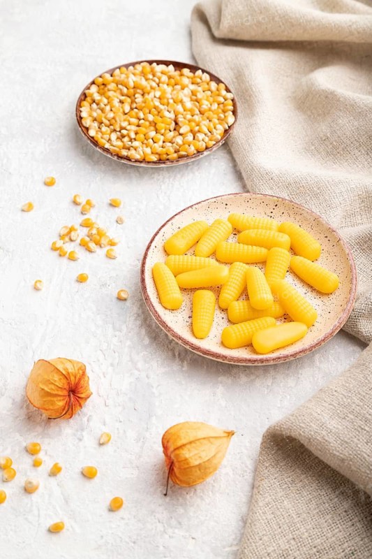 Jelly corn candies on gray concrete background and linen textile. side view, close up