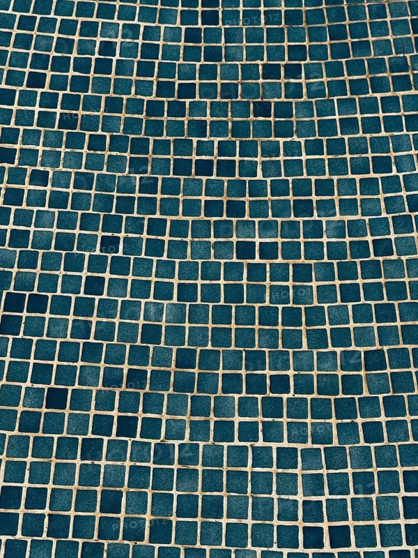A visually captivating abstract image of a blue tiled wall, featuring a geometric mosaic pattern. The repetitive squares create an engaging texture and modern aesthetic