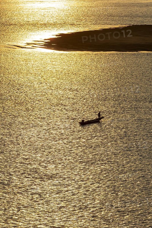Fisherman with longtail boat (Thai: Ruea Hang Yao) at sunrise, Mekong between Thailand and Laos