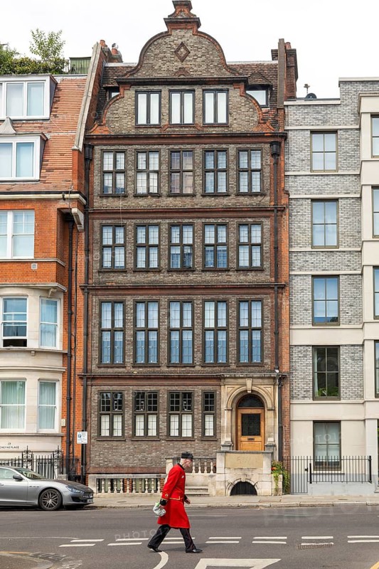 Chelsea pensioner in red uniform walking on street past, 19 Cheyne Place, Royal Hospital Road, Chelsea and Kensington, London, England, UK