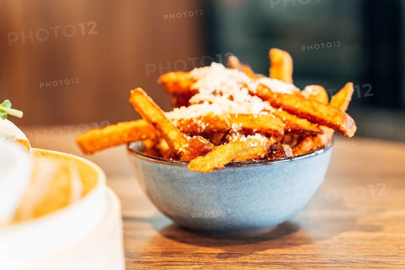 Crispy Sweet Potato Fries with Parmesan and Herbs in a Ceramic Bowl on a Wooden Table