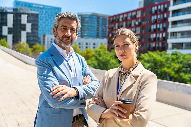 Confident business professionals standing with crossed arms outdoors, embodying leadership and corporate power in a modern city environment with contemporary architecture