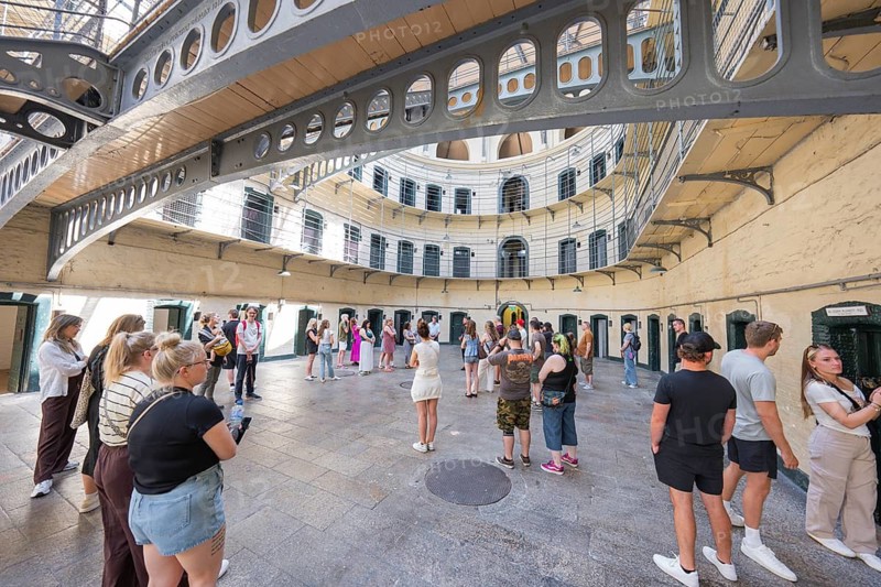 Group of people tour the circular courtyard of a historic building with lattice levels, Kilmainham Gaol Prison, Dublin, Ireland