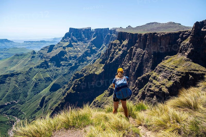 Young hiker looking at the impressive mountains and cliffs of the Drakensberg Mountains, hiking trail on the Sentinel Hiking Trail, Drakensberg, KwaZulu-Natal, South Africa