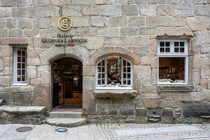 The inviting shop front of the traditional biscuiterie and chocolaterie Maison Georges Larnicol in a century-old, artfully constructed stone building in the historic city center, Roscoff, Finistère department, Brittany region, France