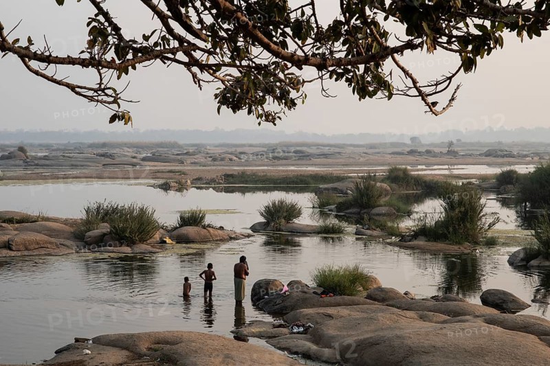 A father and his sons are bathing in the Mahanadi river in the wee hours (Odisha, India), in winter during the dry season