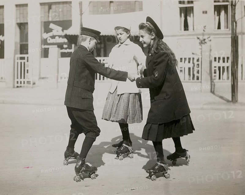 Berlin, roller skating, children, girls, boys, leisure, fun, middle class, three children in historic clothing roller skate together on a street, Phlipp Kester, around 1906