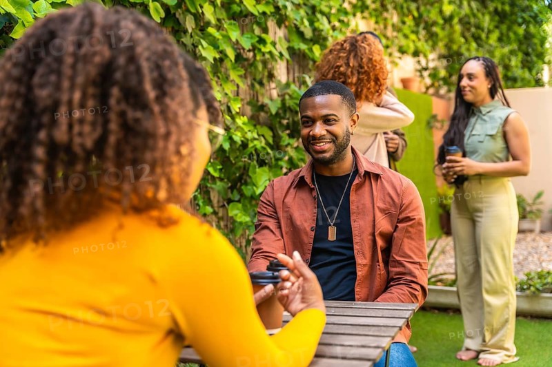 Diverse group of people participating in an outdoor group therapy session, engaging in conversation, smiling, and finding support while sharing experiences in a casual setting